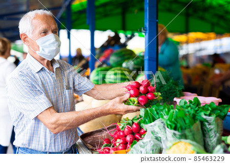 retired european man wearing medical mask protecting against the virus buying radishes and cabbage in market retired european man wearing medical mask protecting against the virus buying radishes and cabbage in market 85463229