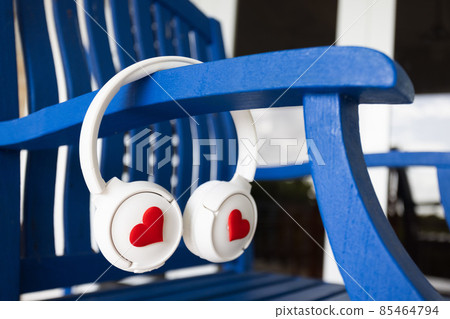 Headphones with hearts are hanging on blue wooden chair. Headphones with hearts are hanging on blue wooden chair. 85464794