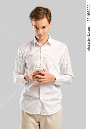 Young handsome man typing on smartphone and looking from under the forehead 85464992