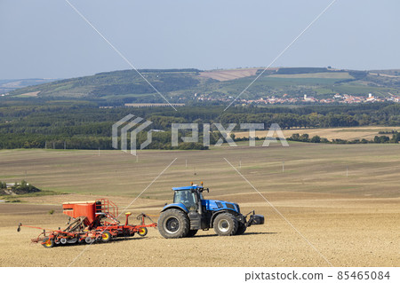 Tractor with seed drill in early spring landscape 85465084