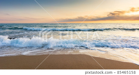 golden sand on the beach in summer. beautiful glowing clouds above the horizon. panoramic seascape at sunrise. relaxing summer mood in morning light. vacation concept background golden sand on the beach in summer. beautiful glowing clouds above the horizon. panoramic seascape at sunrise. relaxing summer mood in morning light. vacation concept background 85465158