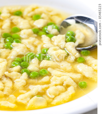 chicken bouillon with homemade dumplings and green peas 85465223