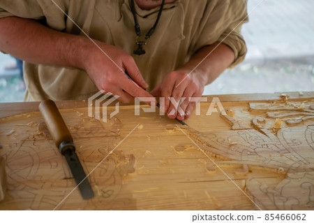 Carpenter carving wood with chisel at medival festival - close up Carpenter carving wood with chisel at medival festival - close up 85466062
