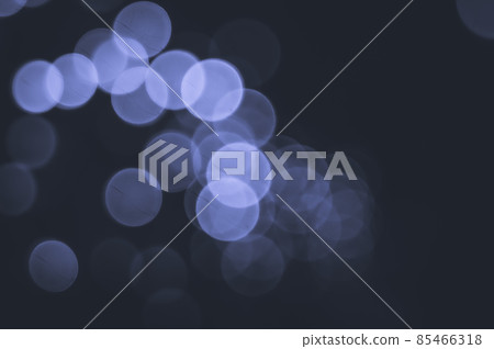 Unfocused bokeh lights in the dark. Abstract background of the lights is out of focus. Colored in trendy color of year 2022 Very Peri. Selective focus, copy space. 85466318