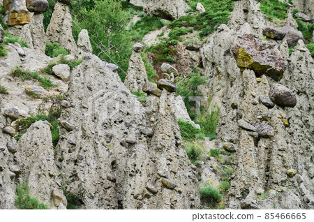 High rock formation with stone boulders at the top, standing on the side of a hill. Stone mushrooms, Altai, Siberia, Russia. 85466665