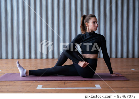 Fit woman working out, stretching while sitting on the floor 85467072