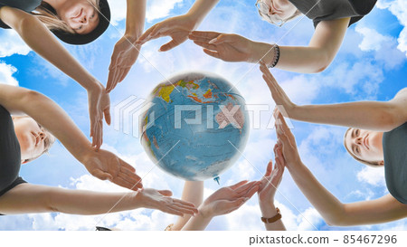 Schoolgirls hug the earth globe with their hands, making a circle out of them on the background of the magic sky. Schoolgirls hug the earth globe with their hands, making a circle out of them on the background of the magic sky. 85467296