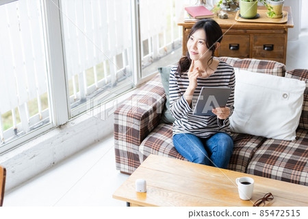 Female looking at a tablet PC in the living room Female looking at a tablet PC in the living room 85472515