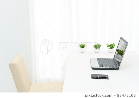 Laptops, writing utensils and foliage plants on a white table 85473108
