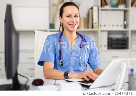 Young female doctor in an office typing on a computer 85474378
