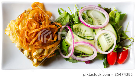 Slice of quiche Lorraine with fried onion rings and salad Slice of quiche Lorraine with fried onion rings and salad 85474395