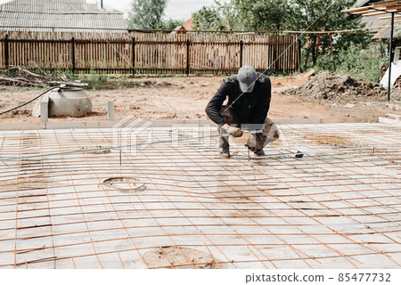male construction worker installs metal fittings for the foundation of the construction of a house male construction worker installs metal fittings for the foundation of the construction of a house 85477732