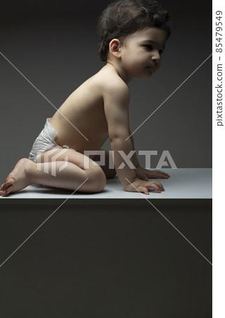 One year old baby with diaper sit on a white table surface One year old baby with diaper sit on a white table surface 85479549