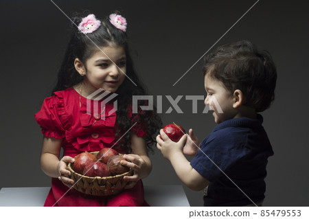 Little girl with her brother holding a pomegranates basket Little girl with her brother holding a pomegranates basket 85479553