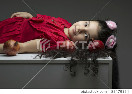 Lie down little girl with three pomegranates around of her hair happy yalda Iranian celebration theme Lie down little girl with three pomegranates around of her hair happy yalda Iranian celebration theme 85479554