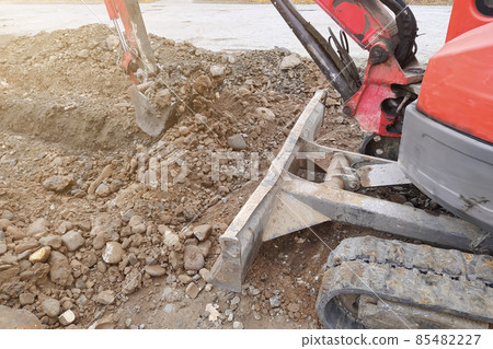 An excavator digs a trench for sewage and rainwater along the side of the road. An excavator digs a trench for sewage and rainwater along the side of the road. 85482227