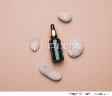 brown glass bottle with a pipette stands on a brown background. Container for cosmetics 85482702