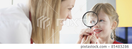 Pediatrician doctor with little girl holding magnifying glass. Pediatrician doctor with little girl holding magnifying glass. 85483286