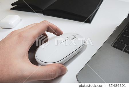 Computer white mouse in hand with notepad and laptop on a white background in banner format 85484801