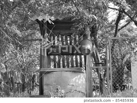 Old well with iron bucket on long forged chain for clean drinking water 85485936