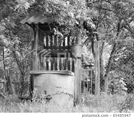 Old well with iron bucket on long forged chain for clean drinking water Old well with iron bucket on long forged chain for clean drinking water 85485947