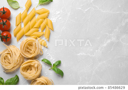 Flat lay composition with different types of pasta on light grey table. Space for text 85486629