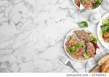 Tasty buckwheat porridge with meat on white marble table, flat lay. Space for text Tasty buckwheat porridge with meat on white marble table, flat lay. Space for text 85486663