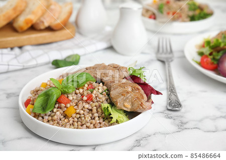Tasty buckwheat porridge with meat on white marble table Tasty buckwheat porridge with meat on white marble table 85486664