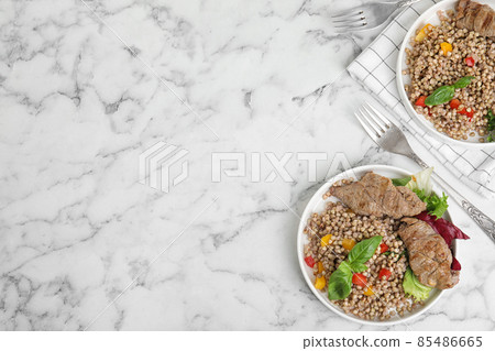 Tasty buckwheat porridge with meat on white marble table, flat lay. Space for text Tasty buckwheat porridge with meat on white marble table, flat lay. Space for text 85486665
