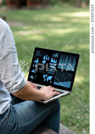 Woman Busy Typing On Laptop Sitting Outside Her Garden Side View Actively Accomplishing Work From Home. Girl Staying Alone Outdoors Finishing Remote Job Projects. 85487024