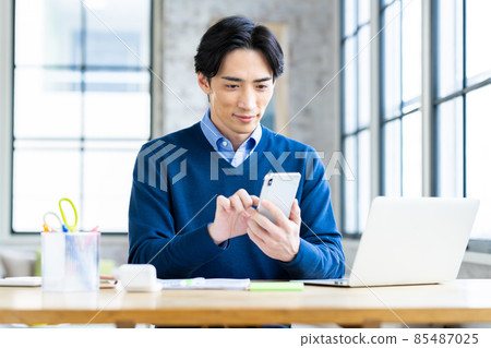Middle-aged man of telework looking at smartphone Middle-aged man of telework looking at smartphone 85487025