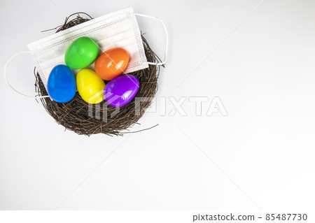 Easter eggs colorful painted in bird nest with protective Face mask top view, Happy Easter Holiday,medical health, Covid-19, coronavirus concept copy space isolated on white background 85487730