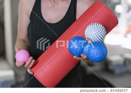 Young athletic woman holds equipment for MFR. Myofascial massage trainer. Different types myofascial rolls. Close up 85488037