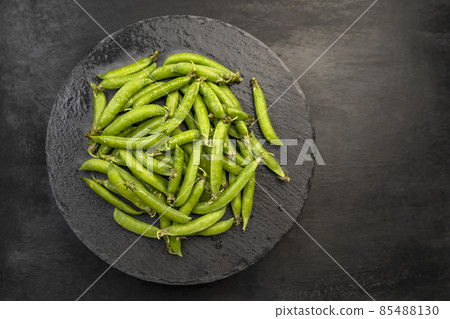 Top view Ripe pods of green peas on black background. Fresh vegetables. Legumes. 85488130