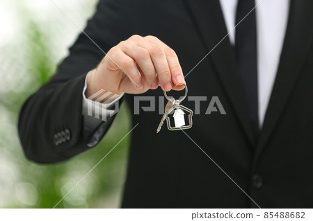 Real estate agent holding house key with trinket on blurred background, closeup Real estate agent holding house key with trinket on blurred background, closeup 85488682