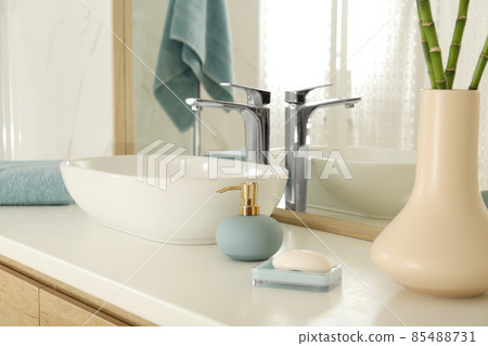 Vessel sink and toiletries near mirror in bathroom Vessel sink and toiletries near mirror in bathroom 85488731