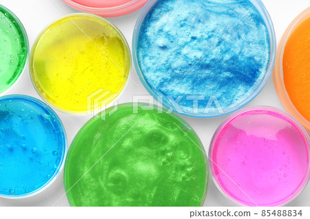 Colorful slimes in plastic containers on white background, top view. Antistress toy 85488834