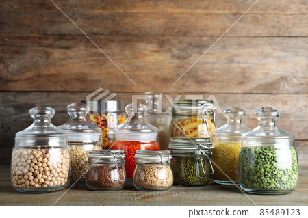 Glass jars with different types of groats and pasta on wooden table Glass jars with different types of groats and pasta on wooden table 85489123