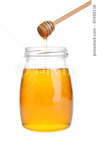 Glass jar of sunflower honey and wooden dipper isolated on white 85489136