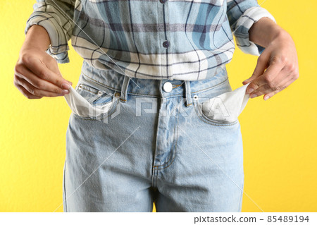 Woman showing empty pockets on yellow background, closeup 85489194