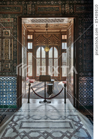 Manial Palace of Prince Mohammed Ali. Entrance of a small room at reception hall with ornate wooden wall and ceiling, decorated wooden windows, lantern and ornate marble floor, Cairo, Egypt Manial Palace of Prince Mohammed Ali. Entrance of a small room at reception hall with ornate wooden wall and ceiling, decorated wooden windows, lantern and ornate marble floor, Cairo, Egypt 85489810