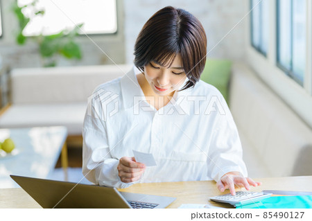 Final tax return image of a young housewife entering a receipt at home 85490127