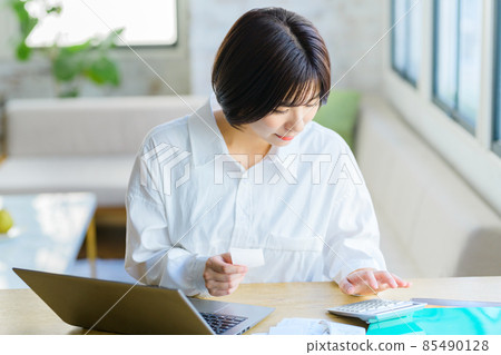 一位年輕家庭主婦在家裡輸入收據的最終納稅申報表圖像 一位年輕家庭主婦在家裡輸入收據的最終納稅申報表圖像 85490128