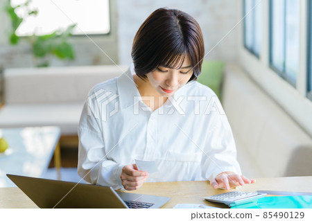 一位年輕家庭主婦在家裡輸入收據的最終納稅申報表圖像 85490129