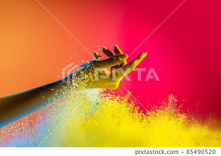 Female hand and explosion of colored, neoned powder on pink studio background with copy space. Magazine cover, wallpaper design 85490520