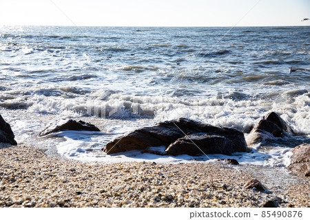 Waves crashing against the rocks from the blue sea beyond the horizon 85490876