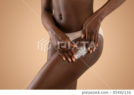 Closeup of black lady applying body lotion on her hips Closeup of black lady applying body lotion on her hips 85492138