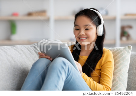 Relaxed chinese child resting on couch with digital tablet Relaxed chinese child resting on couch with digital tablet 85492204