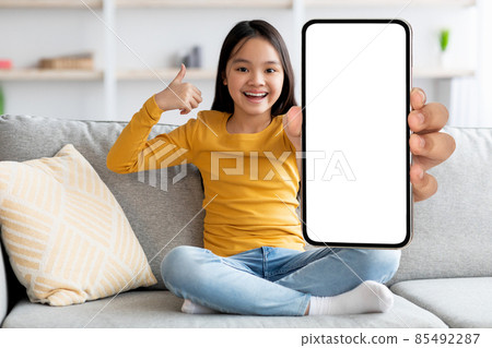 Cheerful asian kid showing cellphone with blank screen 85492287