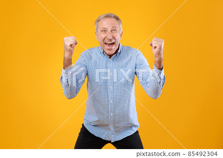 Portrait of excited mature man screaming with raised fists 85492304